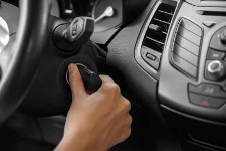 A womans hand starts the car with a key.
