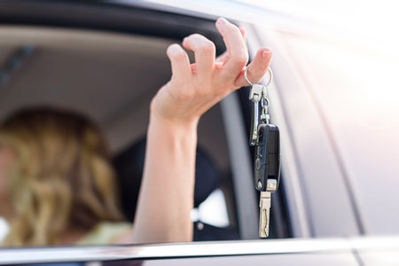 A beautiful blonde woman holds a car key in her hand.の写真素材