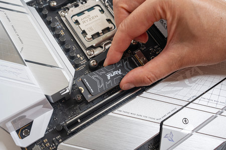 Installing an M2 SSD Kingston FURY Renegade on a PC motherboard during assembly.