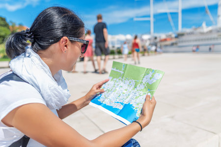 A young woman tourist studies a city map on the street.
