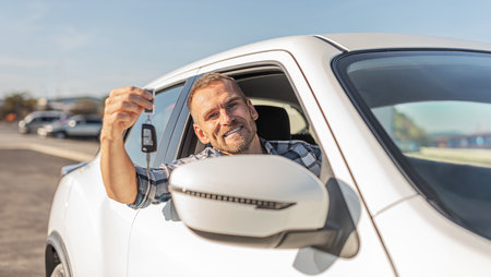 Attractive man holding keys against white car background.の写真素材