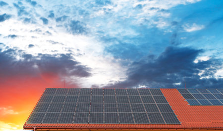 A set of solar panels is installed on the roof of a building with red tiles.の写真素材