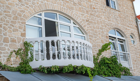 A charming stone building facade with arched windows, a white balustrade balconyの写真素材