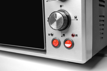Close-up of red power switches and a control knob on a modern stainless steel electric oven