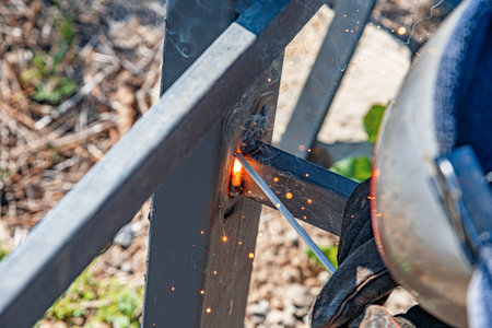 A worker welding two metal beams together outdoors