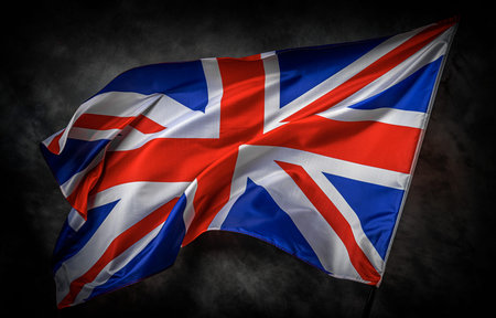 The Union Jack flag of the United Kingdom waves proudly against a dark textured background