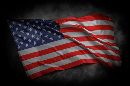 A dramatic image of the American flag waving against a dark cloudy background