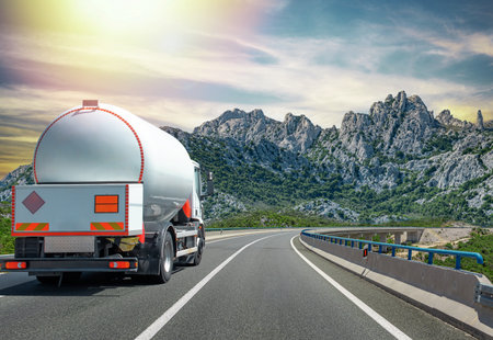 A large tanker truck transporting fuel drives along a curved highwayの写真素材