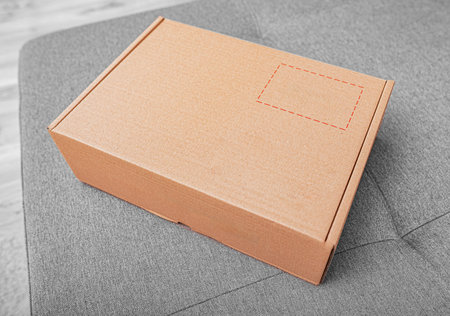 A clean, blank cardboard shipping box rests on a gray textured surface