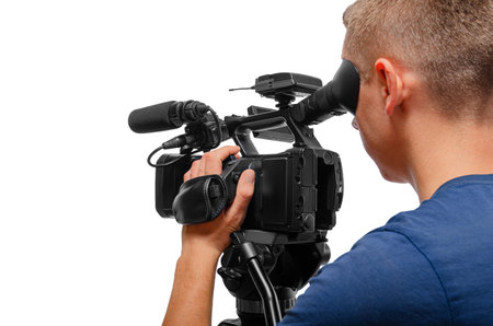 A professional cameraman operating a video camera on a tripod, against a white background.