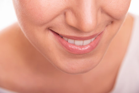 Smiling woman showing her white teeth and natural lips, representing happiness, confidence, and dental health.の写真素材