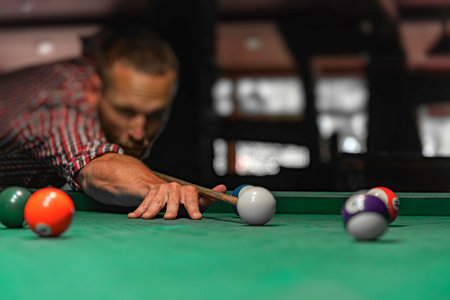 A focused man is lining up a shot in a game of billiards on a green felt tableの写真素材