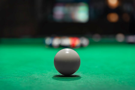 A single, white ball rests on a vibrant green pool tableの写真素材