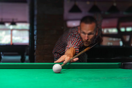 A focused man is lining up a shot in a game of billiards on a green felt tableの写真素材