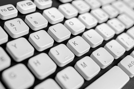 A white computer keyboard with black lettering on a dark surface.