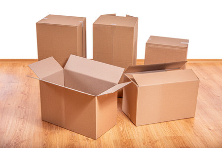 A collection of various sized brown cardboard boxes on a wooden floor.