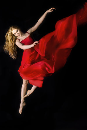 Dramatic image of a woman wearing red dress  jumping over  on a black background 