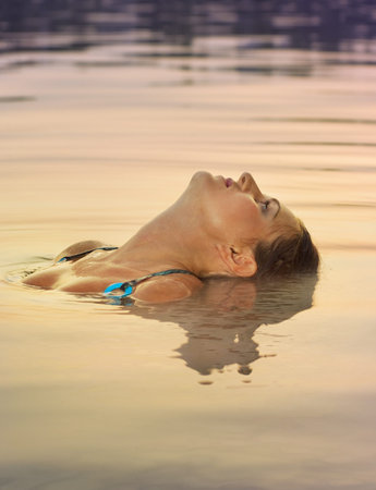 Sexy girl relaxing in  water on sunset