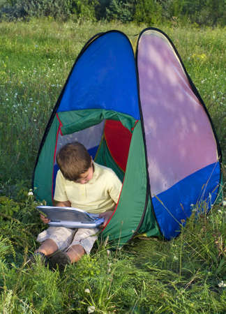 boy with laptop in tent sunny day の写真素材