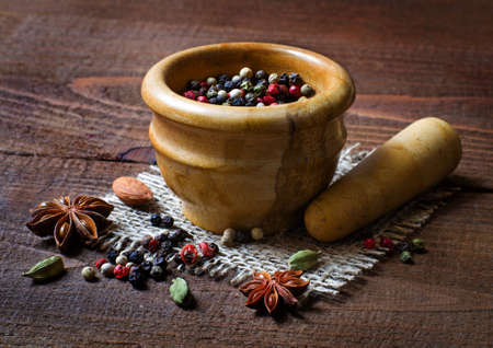 mortar and pestle full of different spices  on old wooden table の写真素材