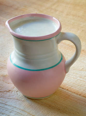 Milk in clay jug on wooden background の写真素材