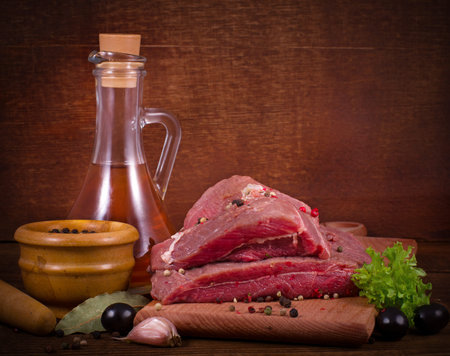 Crude meat and spice on wooden background