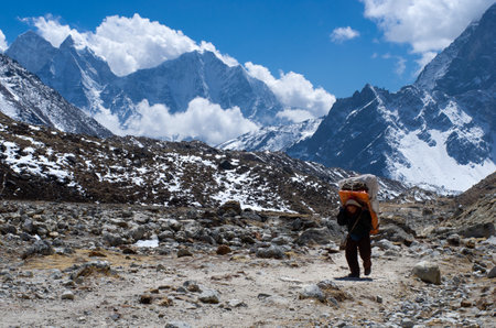 SAGARMATHA NATIONAL PARK, NEPAL - MARCH 16: Porters carry heavy load in the Himalaya  on March 16, 2014 in Sagarmatha National Park, Nepal のeditorial素材