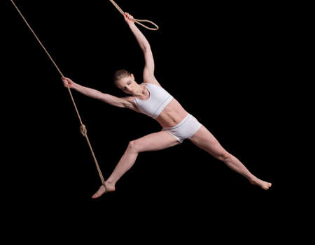 Young woman gymnast on rope on black backgroundの写真素材