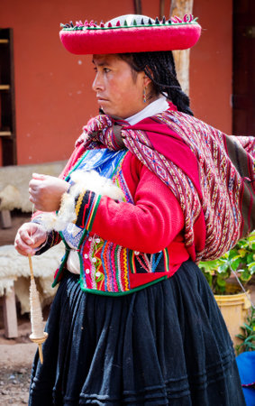 CHINCHERO, PERU - MARCH 9, 2015: Peruvian woman dressed in traditional clothes while working on a homemade wool industry using traditional techniques.のeditorial素材