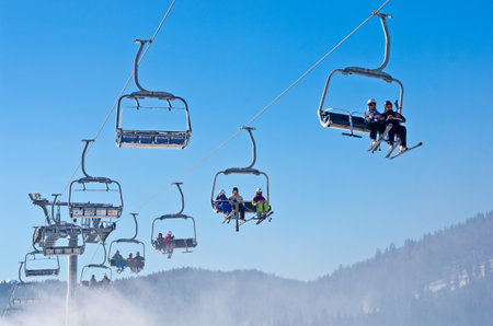 BUKOVEL, UKRAINE - DEC 31, 2015: Skiers and snowboarders on a ski lift in Bukovel. Bukovel is the most popular  Ukranian mountain resort.のeditorial素材