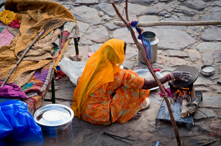 JAIPUR, INDIA - SEPT 26: An unidentified woman makes meal next the road on September 26, 2013 in...