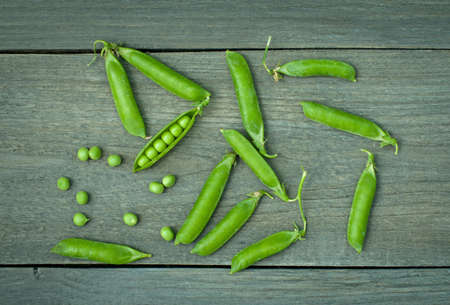 pods of green peas on old wooden background .の写真素材