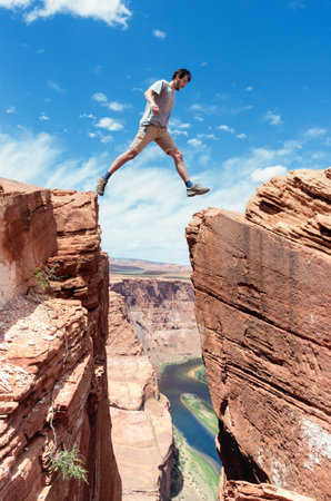 traveler jumps over rock at Horseshoe Bend in Utah, USA
