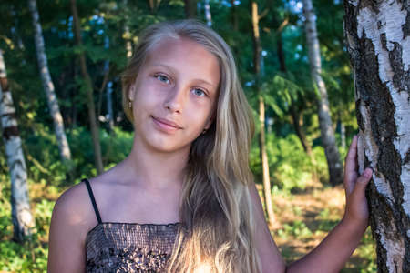 Girl teenager on a background of birch trees.の写真素材