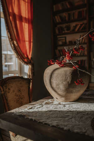 Vintage ceramic vase with rowan branches in afternoon light on a blurred backgroundの写真素材