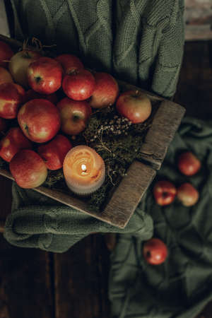Vintage composition with a curtain, old trough, apples and a candleの写真素材
