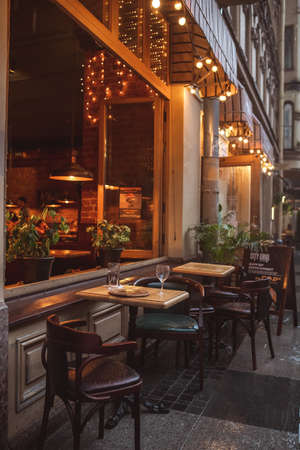 Vintage and loft style cafe with illumination and tables and chairs outsideの写真素材