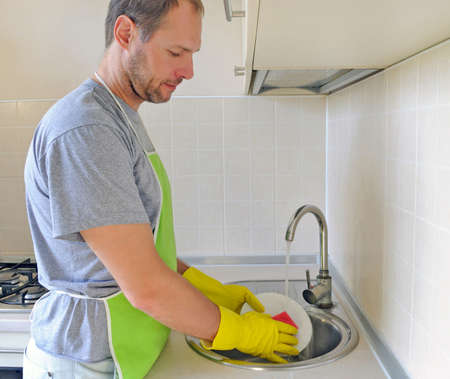 Man washing dish in the kitchenの写真素材