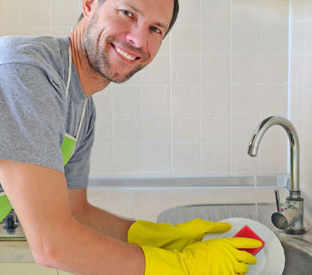 Smiling man washing dish in the kitchenの写真素材