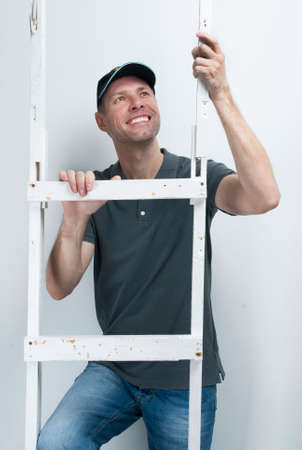 Smiling worker man hold a ladder on a white backgroundの写真素材