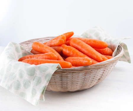 Carrots in wicker basket on white backgroundの写真素材