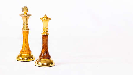 A golden Queen chess piece standing near the Opposing King on a white backgroundの写真素材