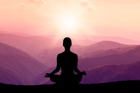 Yoga silhouette on the mountain in sunrays. the dawn sun Yoga silhouette on the mountain in sunrays. the dawn sun