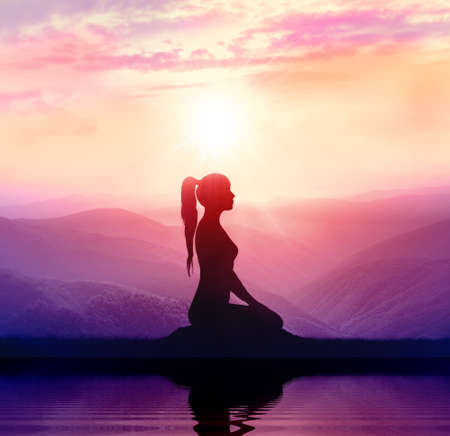 Yoga and meditation. Silhouette of woman in the mountainの写真素材