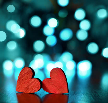 Two red wooden hearts against defocused lights.の写真素材