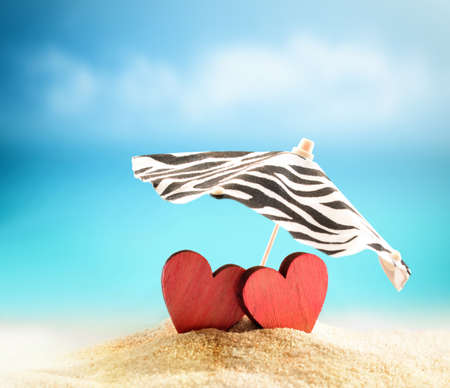 Two hearts under umbrella on the summer beachの写真素材