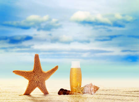 Starfish, seashell and suntan cream on sand beach with ocean, such a summer vacationの写真素材