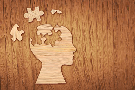 Human head silhouette with a jigsaw piece cut out on the wooden background, mental health symbol....