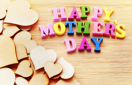 Happy Mothers Day colorful letters spelling greeting on rustic wood table with heartsの写真素材
