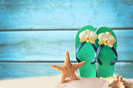pair of flip-flops stuck on the sand of a beach and starfish